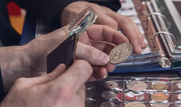 A numismatist examining a coin with a magnifier