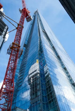 A red building crane next to a glass wall skyscraper